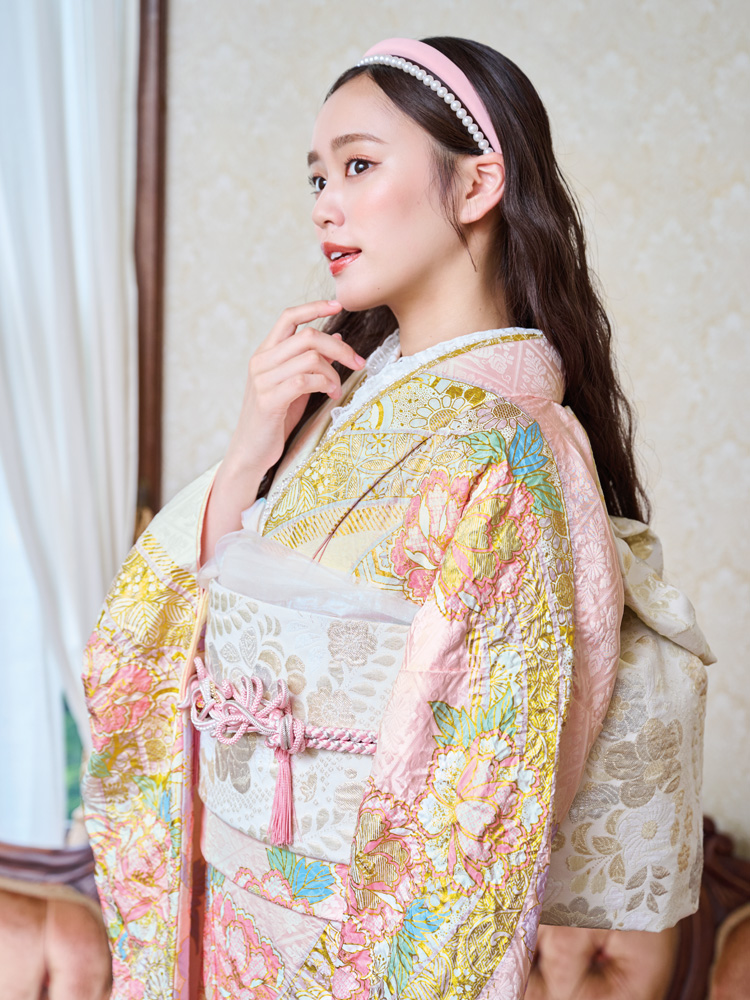 生成りに近い白地に、淡いピンクやゴールドの花々を絞りの技法で贅沢に描き出した華やかな振袖。