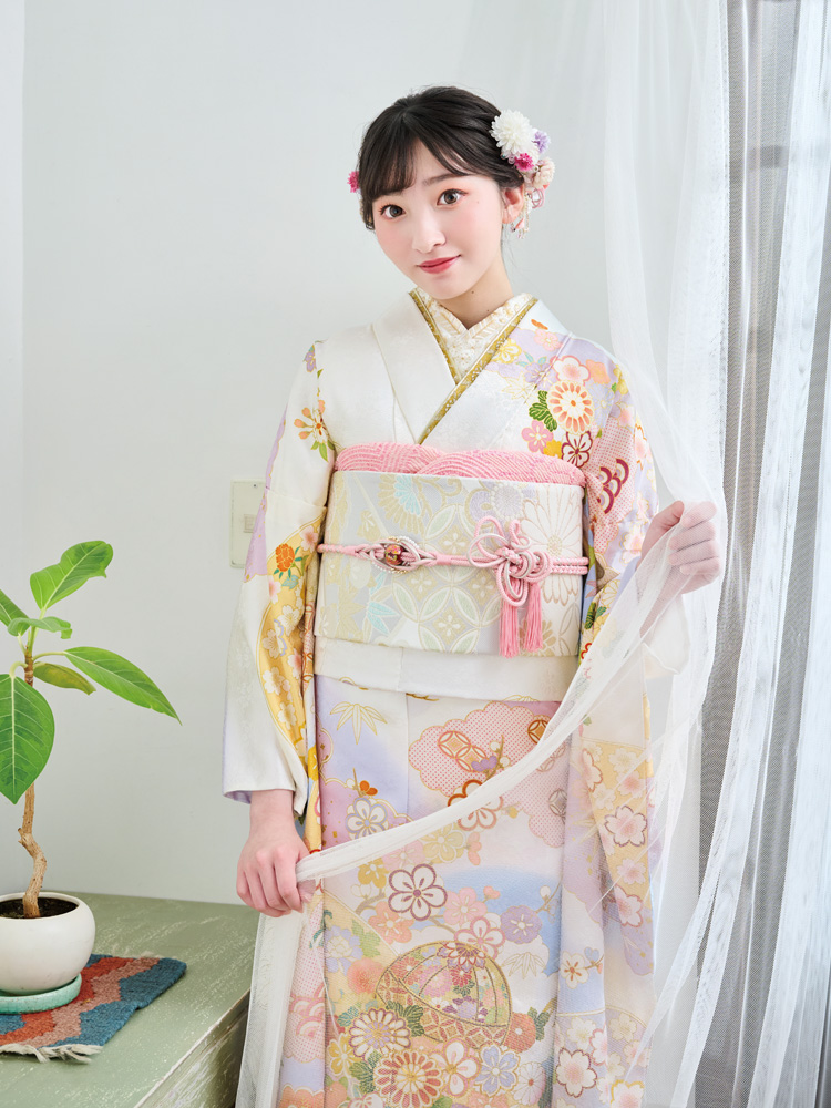 淡いラベンダーからクリーム色へと移ろう地色に、梅や桜、菊などの四季花が華やかに描かれた古典柄の振袖。