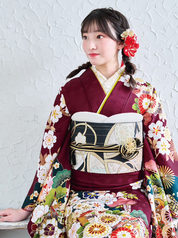 深いえんじ色に桜や菊、松など四季の花々をあしらった、王道の古典柄振袖。