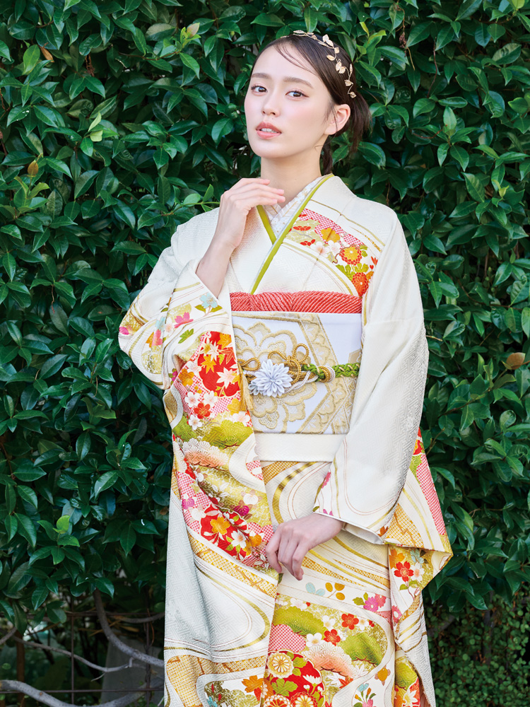 白地の振袖に、赤や橙の花々が色鮮やかに咲き誇り、金彩の流れるような曲線が優雅さを添える一着。