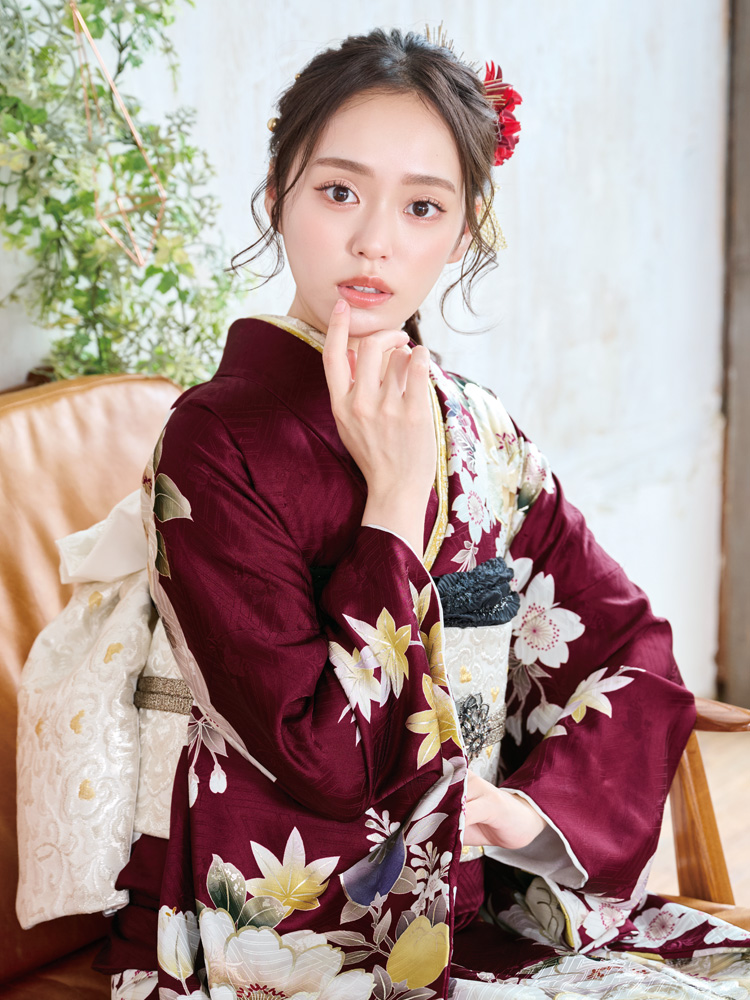 深い臙脂色を基調に、白や紫、黄色の花々が咲き誇る華やかな振袖。